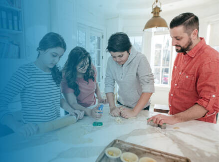 A family of four cooking together in the kitchen.